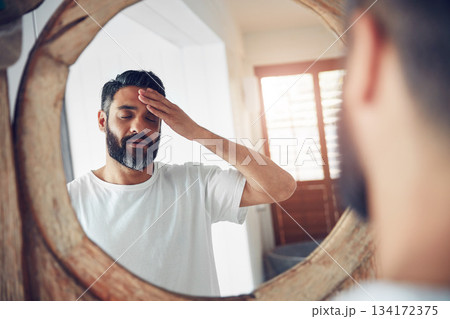 Stress, headache and man by a mirror in the bathroom while doing a skincare routine in his home. Migraine, tired and mature male person doing a health dermatology face treatment in his modern house. 134172375