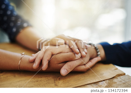 Holding hands, support and closeup with trust, solidarity and community on a home table. Therapy, diversity and gratitude of friends together with hope, respect and love for grief empathy and forgive 134172394