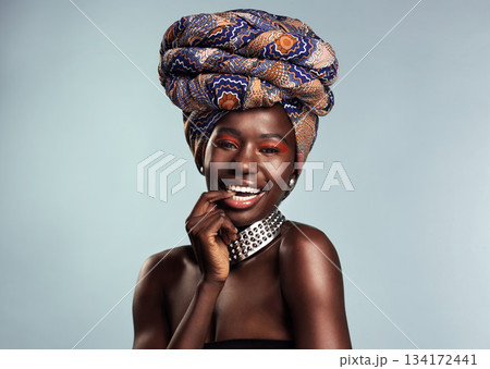 Happy black woman in African turban, fashion and beauty with makeup isolated on studio background. Natural cosmetics, smile in portrait and female model in traditional head wrap, playful and style Happy black woman in African turban, fashion and beauty with makeup isolated on studio background. Natural cosmetics, smile in portrait and female model in traditional head wrap, playful and style 134172441