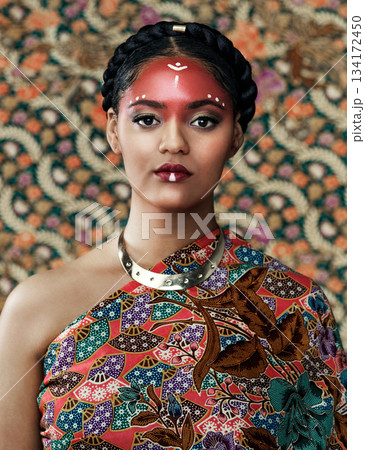 Makeup, portrait and a woman with fashion for culture isolated on a studio background or wall. Face paint, tribal goddess and a young model with traditional, cultural or clothes for a celebration 134172450