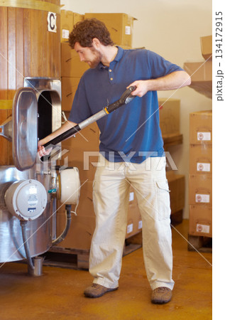 Beer, distillery and person manufacturing alcohol drink in the brewery industry or working on the fermentation process. Product, labour and young man making a craft in a storage or warehouse Beer, distillery and person manufacturing alcohol drink in the brewery industry or working on the fermentation process. Product, labour and young man making a craft in a storage or warehouse 134172915