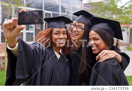 Education, women celebrating graduation with selfie and group at the ceremony outside on campus. University or college academic achievement, female students take photo and people dressed in cloaks Education, women celebrating graduation with selfie and group at the ceremony outside on campus. University or college academic achievement, female students take photo and people dressed in cloaks 134173356