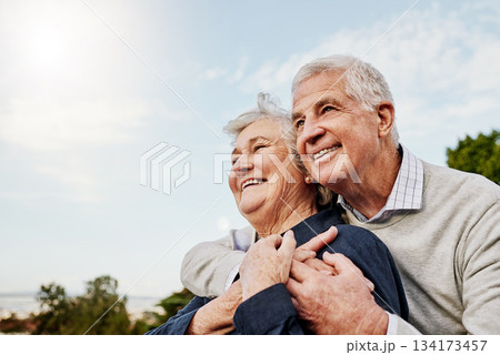 Sky, elderly couple and hug outdoors or happy in retirement or husband and wife in nature. Mature, man and woman smile in vacation or senior citizens care and embrace or date at the park for romance 134173457