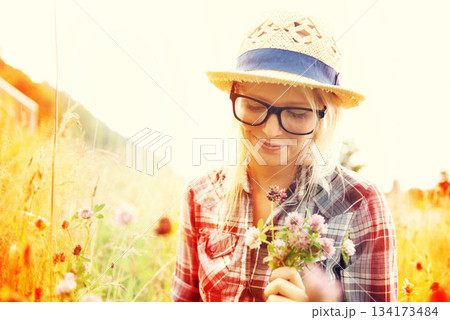 Lens flare, countryside and woman with flowers in field for freedom, wellness and fresh air outdoors. Nature, summer and happy female person in natural meadow for relaxing, calm and peace in morning 134173484