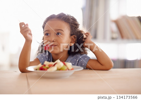 Eating child, breakfast and fruit salad at home with happiness and wellness meal with a smile. House, nutrition and young girl with healthy food and fruits of a hungry kid in the morning at a table 134173566