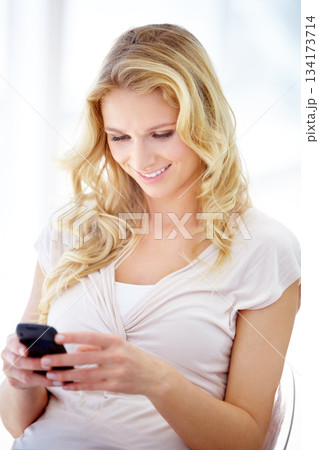 Happy woman, phone and smile for communication, social media or texting while sitting on chair at home. Female person smiling in happiness for chatting, browsing or research on mobile smartphone app 134173714