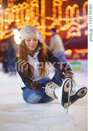 Ice skating, happy and woman tie shoes on rink to start fitness, exercise and workout at night. Skater, smile and female person tying skate laces for winter training, preparing and getting ready. Ice skating, happy and woman tie shoes on rink to start fitness, exercise and workout at night. Skater, smile and female person tying skate laces for winter training, preparing and getting ready. 134174160