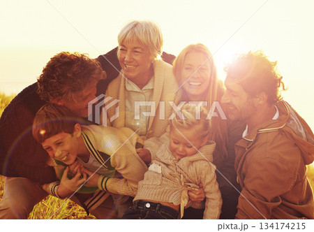Happy, love and big family in nature at sunset hugging, bonding and spending quality time together. Happiness, smile and children posing with their parents and grandparents in outdoor field at dusk. 134174215