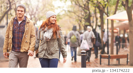 Happy couple, holding hands and walking in city together in winter for romance or travel outdoors. Man and woman having a walk or stroll in park or town in happiness for romantic trip or traveling 134174222