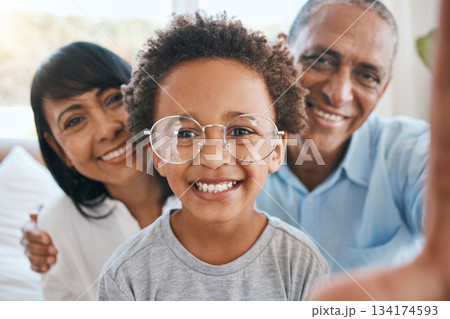 Glasses, grandparents and selfie smile with kid in home living room, bonding and having fun. Photo, happiness and portrait of child with grandma and grandpa taking face pictures for family memory. Glasses, grandparents and selfie smile with kid in home living room, bonding and having fun. Photo, happiness and portrait of child with grandma and grandpa taking face pictures for family memory. 134174593