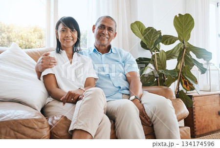 Portrait, senior couple and smile in home living room on sofa, bonding and embrace in house. Couch, retirement and happiness of man and woman relaxing and enjoying quality time together in lounge. Portrait, senior couple and smile in home living room on sofa, bonding and embrace in house. Couch, retirement and happiness of man and woman relaxing and enjoying quality time together in lounge. 134174596