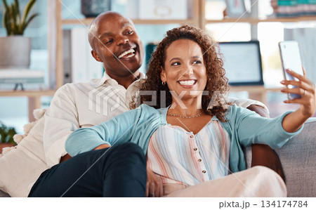 Selfie, happy and couple with smile on sofa for bonding, quality time and relaxing together at home. Marriage, happiness and interracial man and woman take picture for social media, memory and post Selfie, happy and couple with smile on sofa for bonding, quality time and relaxing together at home. Marriage, happiness and interracial man and woman take picture for social media, memory and post 134174784
