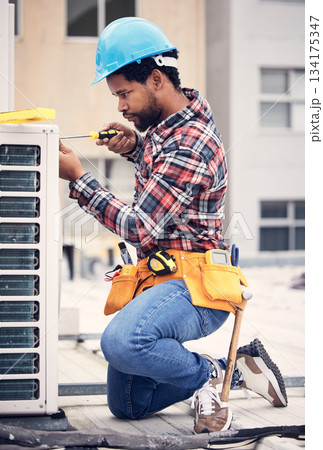 Black man, electrician and maintenance with engineer and ac repair with handyman working with tools on roof. Fix air conditioner, male technician with screwdriver and power generator with service 134175347