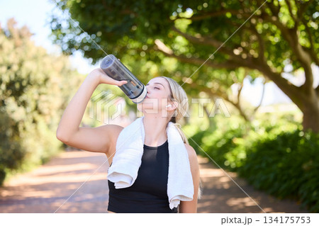 Fitness, runner or woman drinking water in park to hydrate, relax or healthy energy on exercise break in nature. Tired thirsty girl athlete refreshing with liquid for hydration in training or workout 134175753