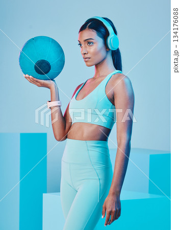 Fitness, ball and woman in studio with music for training, exercise and sports routine on blue background. Headphones, radio and Indian female athlete with weight and podcast, mindset and focus 134176088