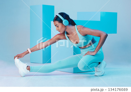 Headphones, stretching and fitness woman isolated on blue background for workout, training or exercise music. Legs, sports and biracial person listening to audio, muscle health and wellness in studio Headphones, stretching and fitness woman isolated on blue background for workout, training or exercise music. Legs, sports and biracial person listening to audio, muscle health and wellness in studio 134176089