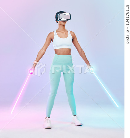 Fitness, virtual reality glasses and woman with lightsaber, futuristic and player against studio background. Female gamer, person or confident girl with vr eyewear, fantasy weapons and laser saber 134176118
