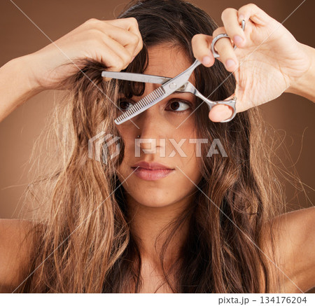 Hair care, damage and woman with scissors, worry and salon cut treatment on brown background. Beauty crisis, haircut and split ends, frustrated latino model with damaged hairstyle on studio backdrop. 134176204