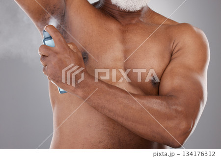 Senior black man, deodorant and spraying armpit for skincare, grooming or personal hygiene against a gray studio background. Elderly African American male applying cosmetics for fresh or clean smell 134176312