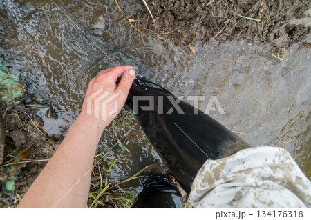 田植えで汚れた長靴の汚れを田んぼの水で洗い流す 134176318