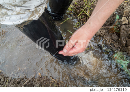 田植えで汚れた長靴の汚れを田んぼの水で洗い流す 134176319