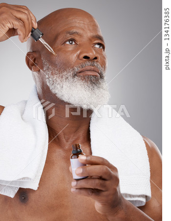 Skincare, health and male with face serum in a studio for a natural, beauty and skin treatment. Cosmetic, wellness and senior man model with facial oil for a dermatology routine by a gray background. Skincare, health and male with face serum in a studio for a natural, beauty and skin treatment. Cosmetic, wellness and senior man model with facial oil for a dermatology routine by a gray background. 134176385
