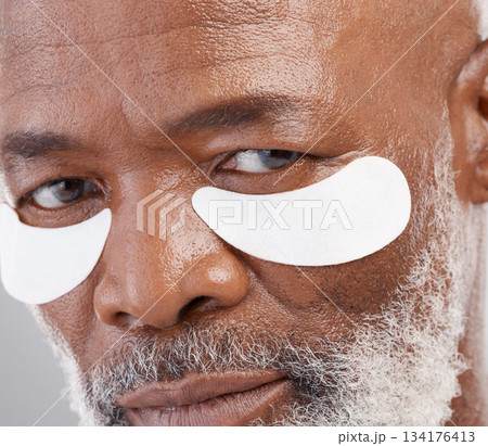 Skincare, eye mask and zoom on portrait of man with serious face and professional anti ageing spa treatment. Dermatology, cosmetic collagen routine and mature African model with skin care on eyes. Skincare, eye mask and zoom on portrait of man with serious face and professional anti ageing spa treatment. Dermatology, cosmetic collagen routine and mature African model with skin care on eyes. 134176413