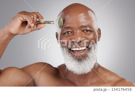 Face roller, portrait and senior black man with skincare smile, stone and dermatology product for skin glow. Elderly, grooming and facial jade roll for male model in self care for anti aging beauty Face roller, portrait and senior black man with skincare smile, stone and dermatology product for skin glow. Elderly, grooming and facial jade roll for male model in self care for anti aging beauty 134176458