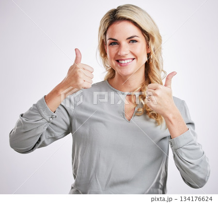Portrait, thumbs up and motivation with a woman on a gray background in studio to say thank you. Face, hands and welcome with an attractive young female indoor to gesture an emoji of support 134176624