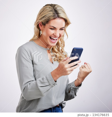 Happy woman, phone and celebration for winning, good news or sale against a white studio background. Excited female with smile on mobile smartphone app in win, discount or bonus promotion and victory 134176635