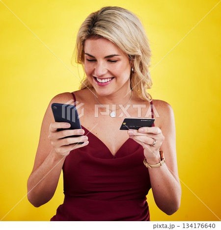 Phone, smile and woman with credit card for online shopping in studio isolated on a yellow background. Cellphone, fintech and happy female person digital banking, financial payment or ecommerce. 134176640