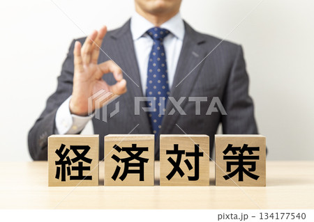 「経済対策」と書かれたブロックとOKポーズをするビジネスマン 134177540