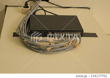 Black network switch connected to many gray Ethernet cables. 134177702