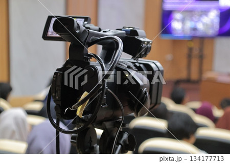 Professional video camera filming presentation in auditorium room. Professional video camera filming presentation in auditorium room. 134177713