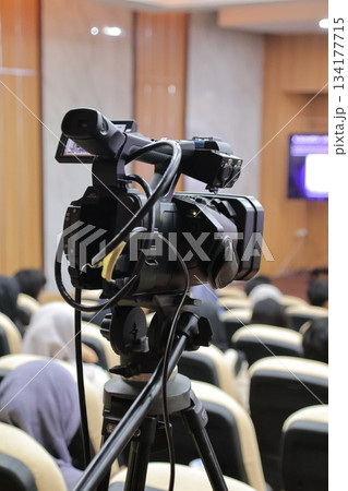 Video camera recording audience at blurred indoor conference hall event. Video camera recording audience at blurred indoor conference hall event. 134177715