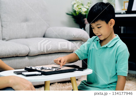young boy concentrating while playing Go at home, pointing to a move on the board during a thoughtful and educational indoor activity that encourages logic, patience, and cognitive development young boy concentrating while playing Go at home, pointing to a move on the board during a thoughtful and educational indoor activity that encourages logic, patience, and cognitive development 134177946