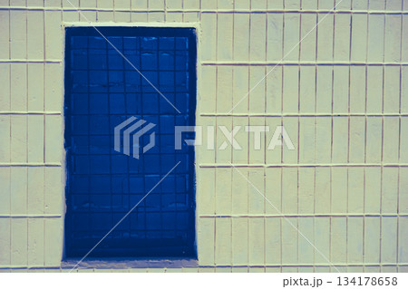 Blue window, bricked up with brick and covered with bars, on a tiled wall Blue window, bricked up with brick and covered with bars, on a tiled wall 134178658