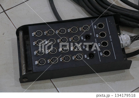 Black stage box audio snake system with multiple XLR connections on tiled floor 134179518