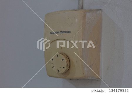 Close up view of dirty electronic controller device with rotary knob on white wall Close up view of dirty electronic controller device with rotary knob on white wall 134179532