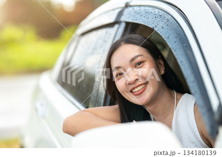 Pretty asian woman looking out from car window while driving a car travel or going on a road trip. 134180139