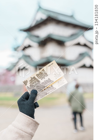 Tourist hand holding Hirosaki castle ticket during sightseeing Sakura Cherry Blossom in Spring season at Hirosaki Castle park. Hirosaki city, Aomori prefecture, Tohoku, Japan, 25 April 2025 134181830