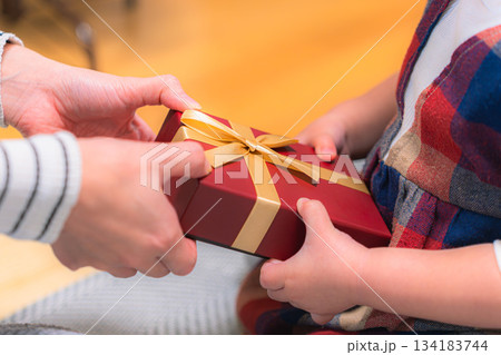 子どもへプレゼントを手渡す瞬間 クリスマスシーズンのギフトシーン 子どもへプレゼントを手渡す瞬間 クリスマスシーズンのギフトシーン 134183744