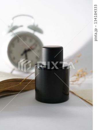 Elegant black bottle sits on a background with aesthetic ornaments with delicate color tones. A perfect vintage charm to a rustic still life, perfect for fashion, fragrance, or lifestyle projects Elegant black bottle sits on a background with aesthetic ornaments with delicate color tones. A perfect vintage charm to a rustic still life, perfect for fashion, fragrance, or lifestyle projects 134184333