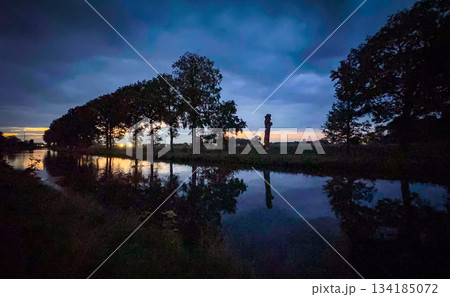 In twilight, reflections dance on the calm riverbank at dusk, creating a picturesque scene 134185072