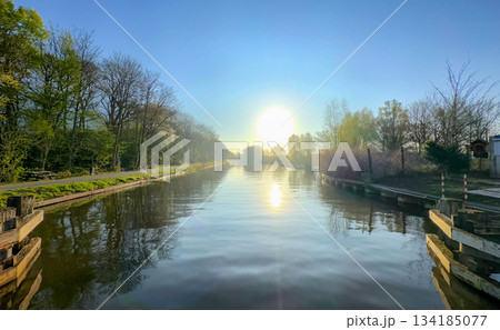 A Serene Sunrise that Spreads Beauty Over a Picturesque Canal Surrounded by Lush Greenery A Serene Sunrise that Spreads Beauty Over a Picturesque Canal Surrounded by Lush Greenery 134185077