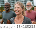 A group of active adults jogging outdoors, smiling and energized, enjoying a healthy lifestyle together in a bright and motivating urban environment. 134185238