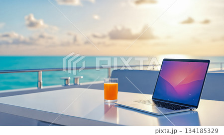Laptop computer and orange juice on white table on luxury yacht deck with ocean background illustrating digital nomad lifestyle 134185329