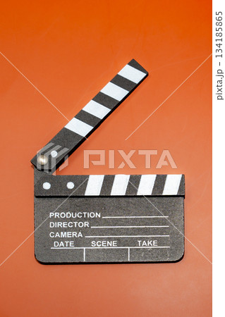A film clapperboard on an orange background, used in the movie industry. The slate is opened to indicate the start of a film. A film clapperboard on an orange background, used in the movie industry. The slate is opened to indicate the start of a film. 134185865