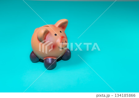 A piggy bank, a symbol of savings, set against a solid backdrop, evokes financial security amid economic downturns. 134185866