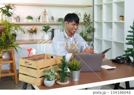 Happy Professional: Individual smiling while working on laptop in a green workspace 134186048